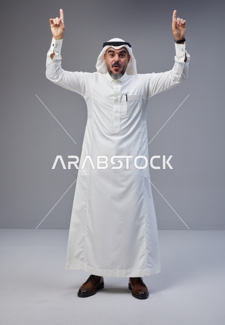 Saudi Man in Traditional Thobe Pointing Up in Studio
