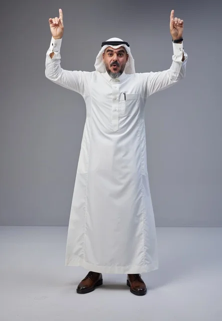 Saudi Man in Traditional Thobe Pointing Up in Studio
