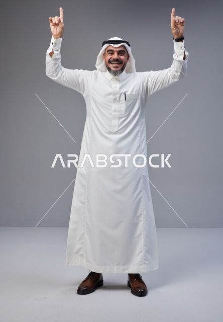 رجل سعودي بالزي التقليدي يشير للأعلى في الاستوديو