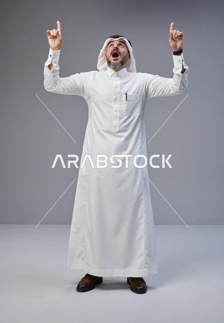 رجل سعودي بالزي التقليدي يشير للأعلى بذهول