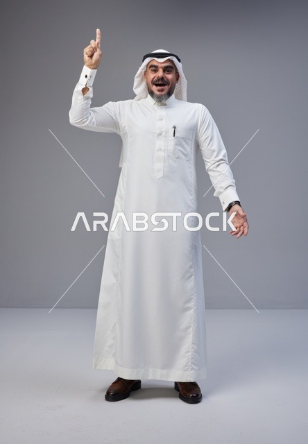 رجل سعودي بالزي التقليدي يشير للأعلى في الاستوديو