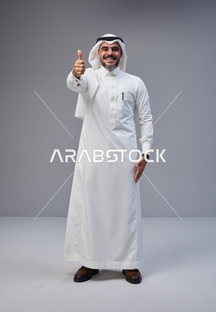 رجل سعودي بالزي التقليدي يشير بعلامة الإعجاب