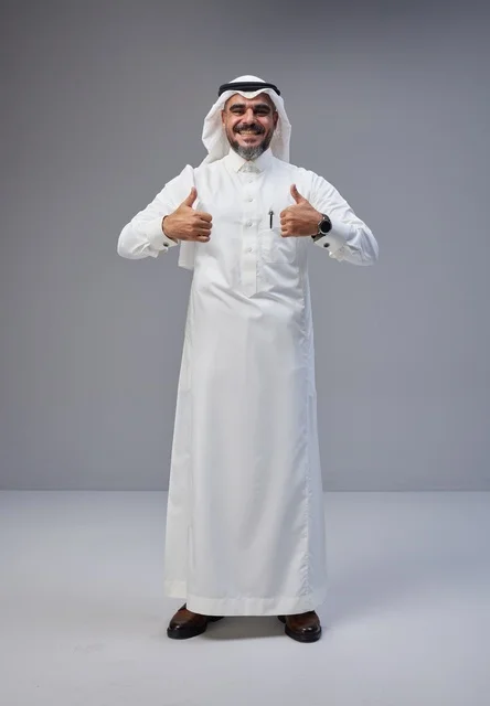 رجل سعودي مبتسم بالزي التقليدي يرفع إبهامه في الاستوديو
