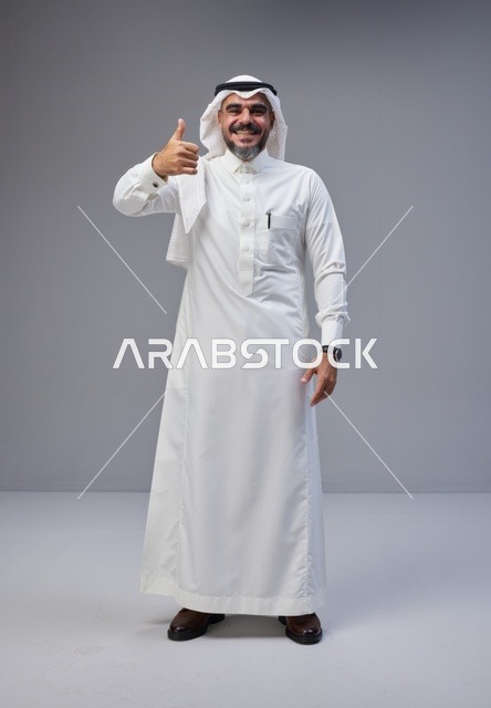 رجل سعودي بالزي التقليدي يشير بعلامة الإعجاب