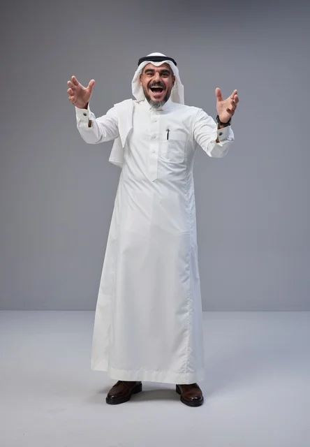 رجل سعودي متحمس بالزي التقليدي في استوديو بخلفية رمادية