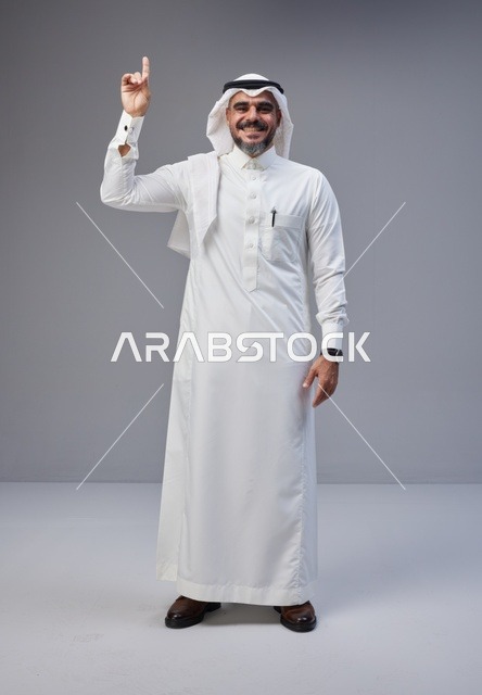 رجل سعودي يشير للأعلى بالزي التقليدي في الاستوديو