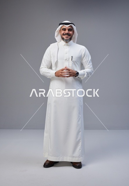 رجل سعودي بالزي التقليدي أمام خلفية رمادية