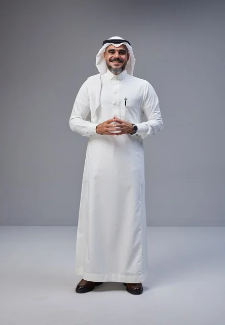 رجل سعودي بالزي التقليدي أمام خلفية رمادية