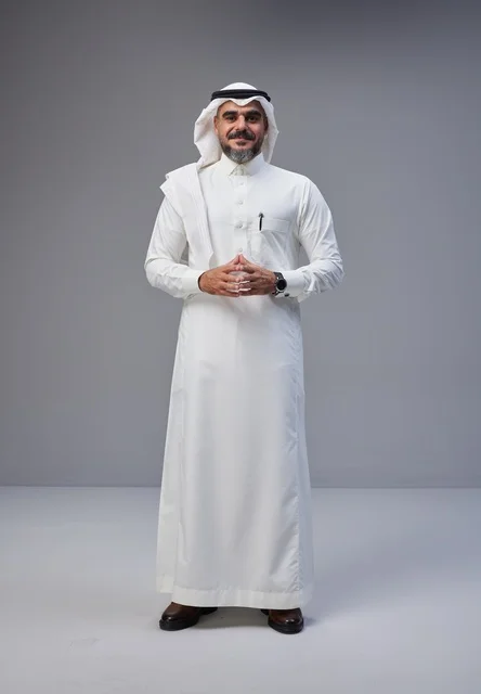 رجل سعودي بالزي التقليدي أمام خلفية رمادية