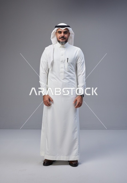 رجل سعودي بالزي التقليدي في استوديو بخلفية رمادية