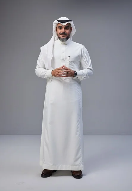 رجل سعودي بالزي التقليدي أمام خلفية رمادية