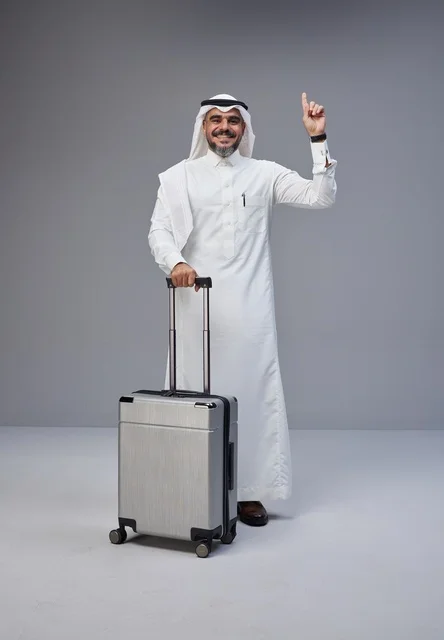 رجل سعودي مع حقيبة سفر يشير للأعلى