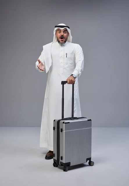 Surprised Saudi Man with Suitcase on Grey Background