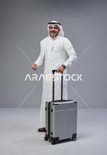 رجل سعودي بالزي التقليدي مع حقيبة سفر فضية
