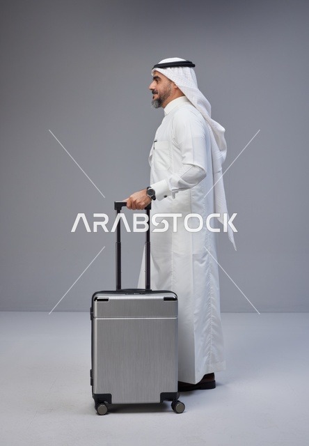 رجل سعودي بالزي التقليدي يقف مع حقيبة سفر