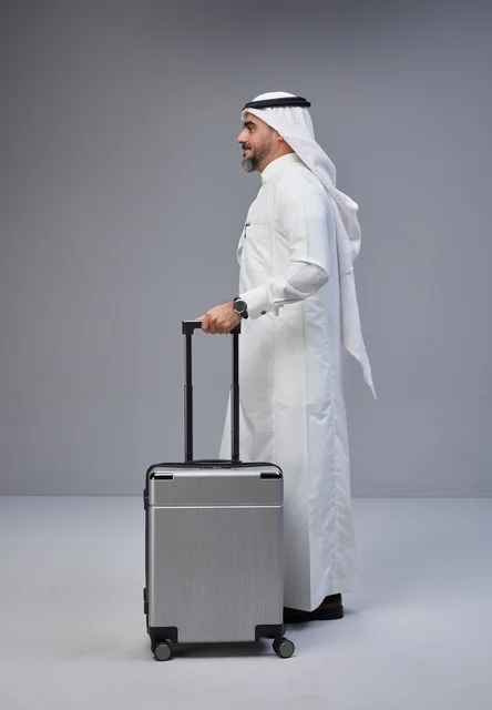 رجل سعودي بالزي التقليدي يقف مع حقيبة سفر
