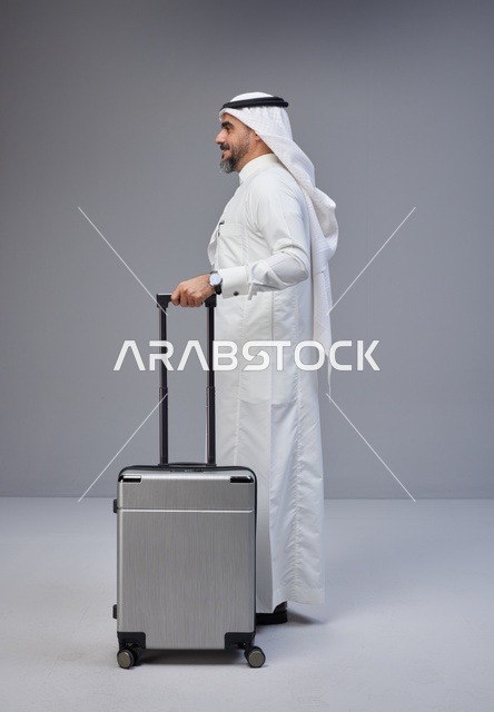 رجل سعودي بالزي التقليدي مع حقيبة سفر فضية