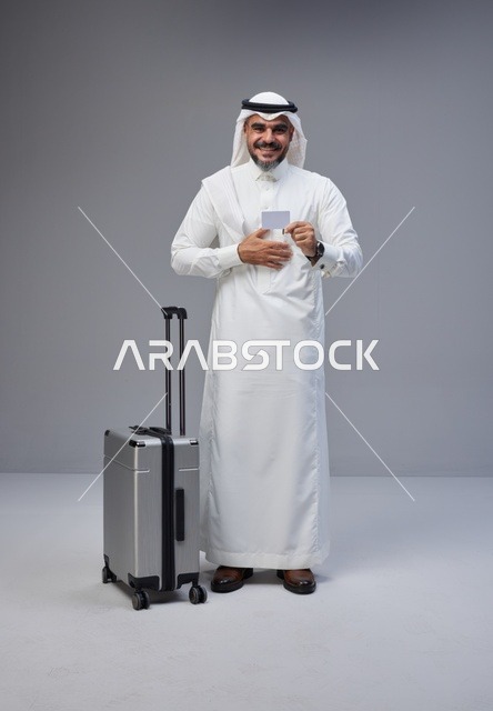 رجل سعودي مع حقيبة سفر يحمل بطاقة ائتمان في استوديو