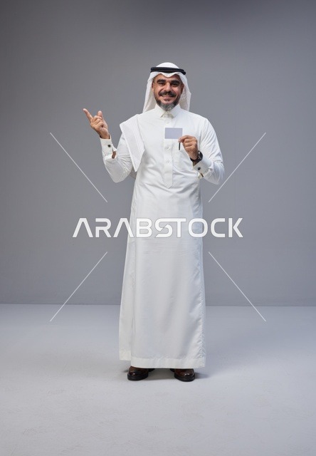 رجل سعودي بالزي التقليدي يحمل بطاقة تعريف فارغة