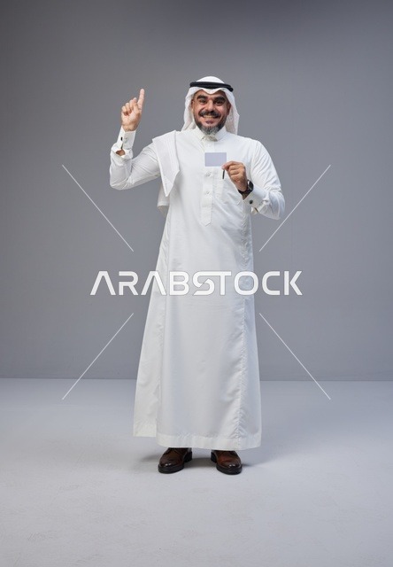 رجل سعودي بالزي التقليدي يحمل بطاقة تعريف فارغة