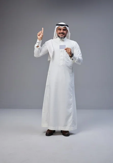 رجل سعودي يحمل بطاقة فارغة ويشير للأعلى في استوديو