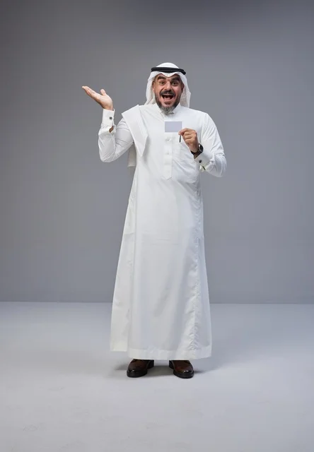 رجل سعودي بالزي التقليدي يحمل بطاقة تعريفية فارغة
