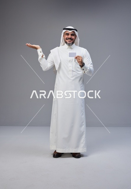 رجل سعودي يحمل بطاقة تعريف فارغة بخلفية رمادية