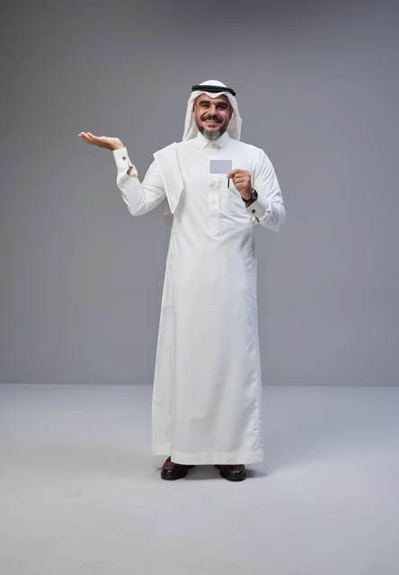 رجل سعودي يحمل بطاقة تعريف فارغة بخلفية رمادية