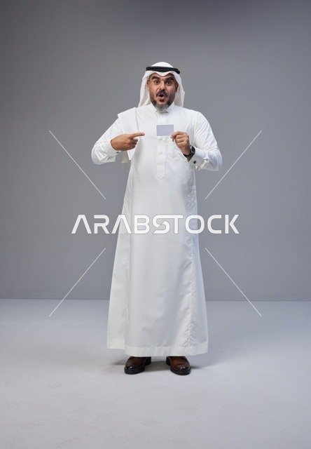 رجل سعودي بالزي التقليدي يحمل بطاقة تعريف فارغة