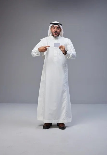 رجل سعودي بالزي التقليدي يحمل بطاقة تعريف فارغة