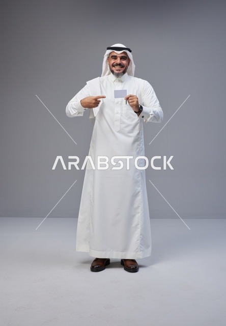 رجل سعودي بالزي التقليدي يحمل بطاقة تعريفية فارغة