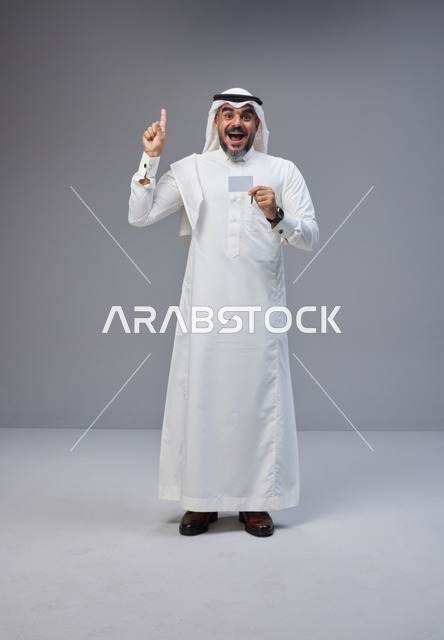 رجل سعودي بالزي التقليدي يحمل بطاقة تعريف فارغة