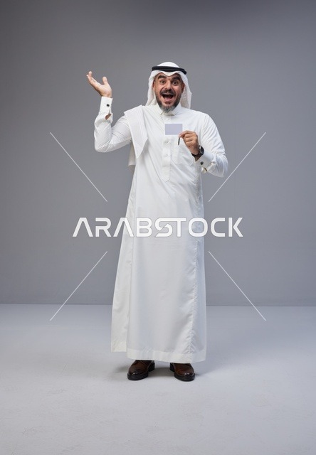 رجل سعودي يحمل بطاقة تعريف فارغة بتعبير مندهش