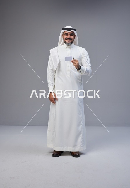 رجل سعودي بالزي التقليدي يحمل بطاقة تعريف فارغة