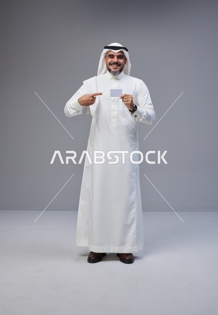 رجل سعودي بالزي التقليدي يحمل بطاقة تعريف فارغة