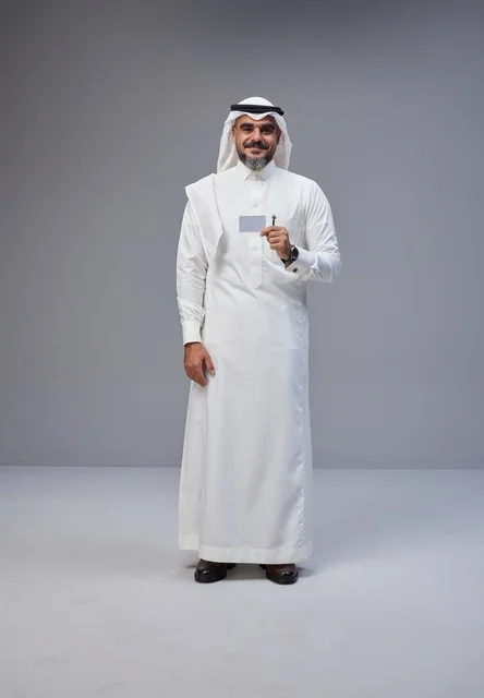 رجل سعودي يحمل بطاقة تعريف فارغة أمام خلفية رمادية