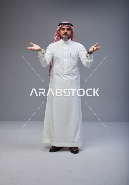 رجل سعودي بالزي التقليدي في استوديو بخلفية رمادية