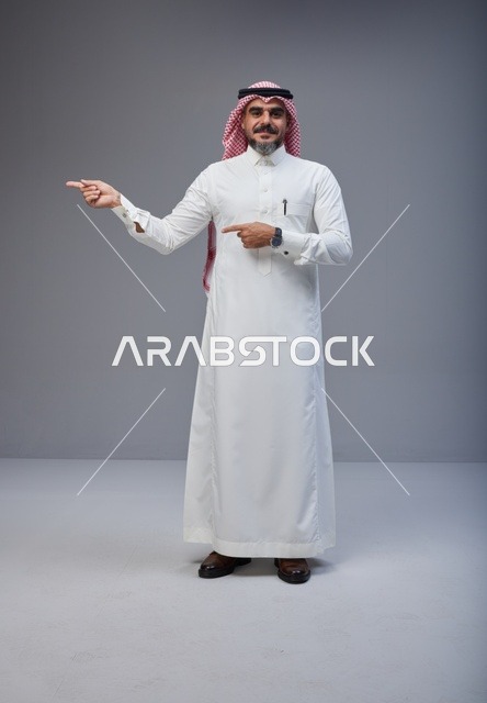 رجل سعودي بالزي التقليدي يشير بيده في استوديو