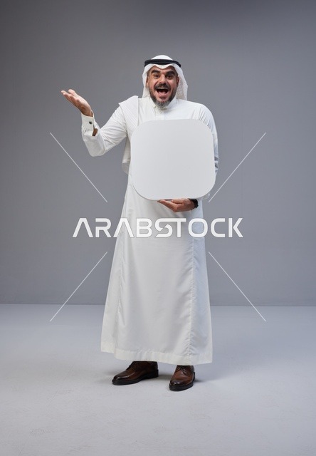 رجل سعودي يحمل لوحة فارغة بتعبير وجه مندهش