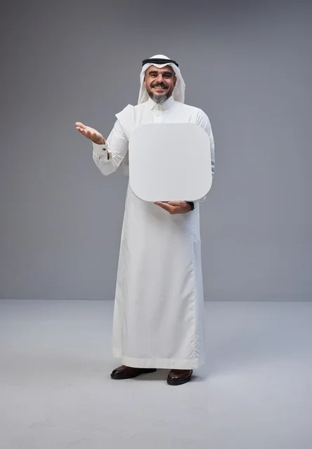 رجل سعودي يحمل لوحة فارغة أمام خلفية رمادية
