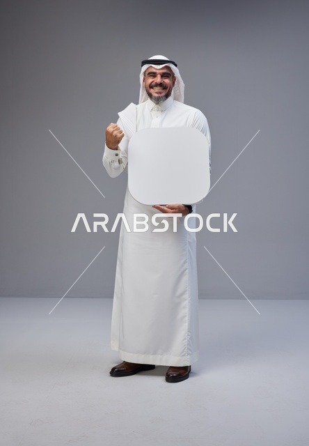 رجل سعودي يحمل لوحة بيضاء فارغة في الاستوديو