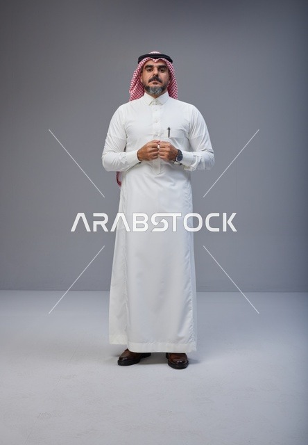 رجل سعودي بالزي التقليدي يقف في استوديو