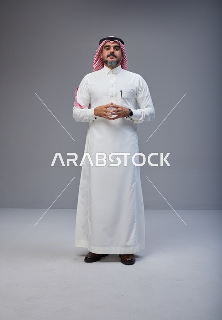 رجل سعودي بالزي التقليدي في خلفية رمادية