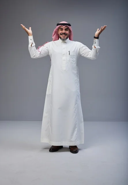 رجل سعودي بالزي التقليدي يبتسم ويرفع يديه