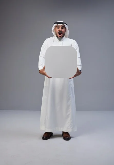 رجل سعودي يحمل لوحة بيضاء فارغة بتعبيرات وجه مندهشة