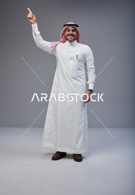 Smiling Saudi Man in Traditional Thobe Pointing Upward