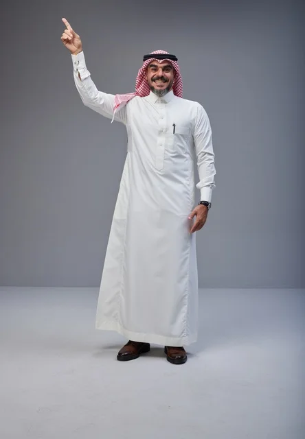 Smiling Saudi Man in Traditional Thobe Pointing Upward