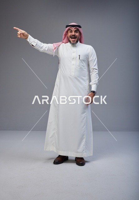 رجل سعودي بالزي التقليدي يشير في الاستوديو