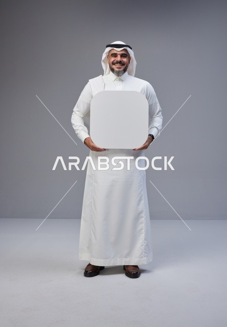 رجل سعودي يحمل لوحة بيضاء فارغة في الاستوديو