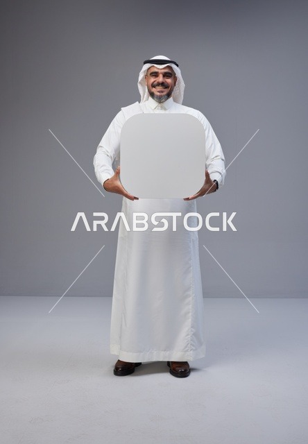 رجل سعودي يحمل لوحة بيضاء فارغة في الاستوديو